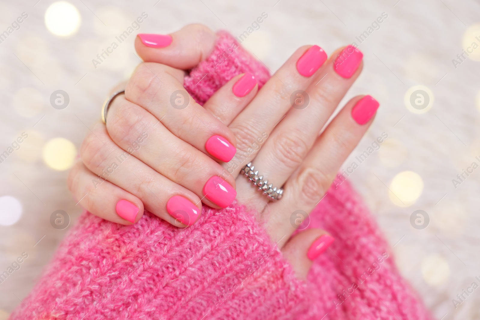 Photo of Woman showing her manicured hands with pink nail polish on faux fur mat, closeup