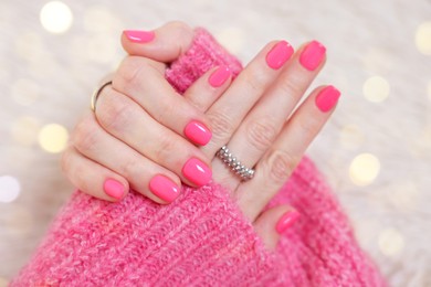 Woman showing her manicured hands with pink nail polish on faux fur mat, closeup