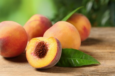 Photo of Cut and whole fresh ripe peaches on wooden table against blurred background, closeup. Space for text