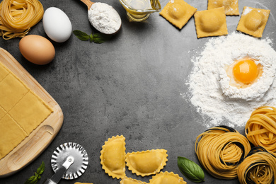Flat lay composition with different types of pasta on grey table. Space for text
