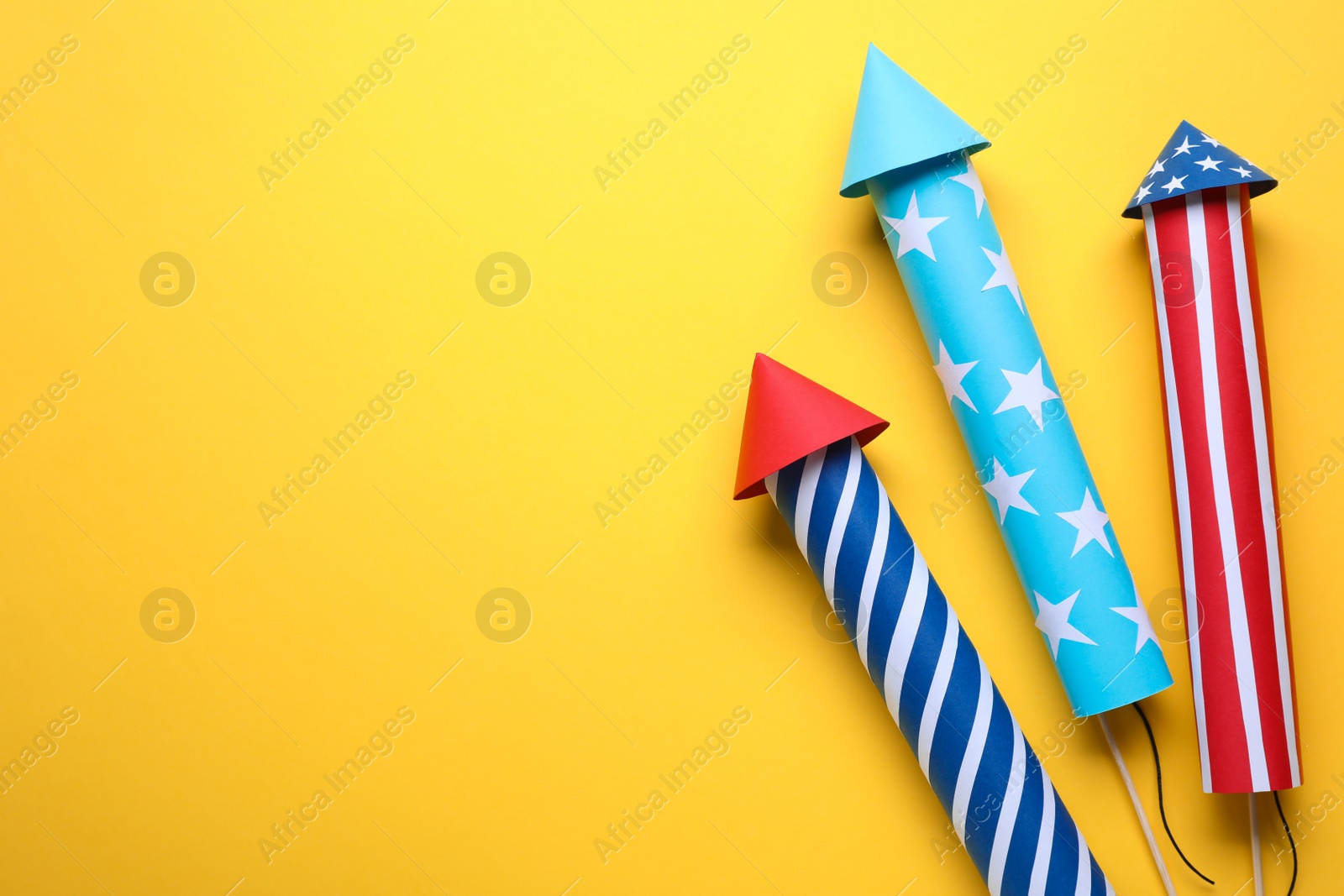 Photo of Firework rockets on yellow background, flat lay with space for text. Festive decor