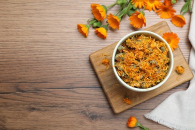 Photo of Dry and fresh calendula flowers on wooden table, flat lay. Space for text