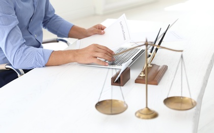 Photo of Male notary working with laptop at table in office, closeup