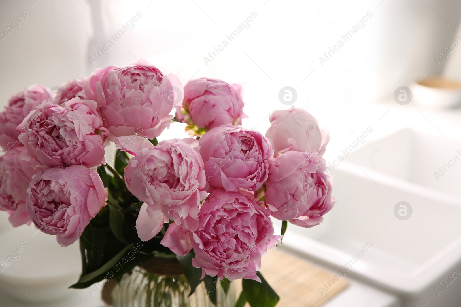 Photo of Vase with bouquet of beautiful pink peonies in kitchen, closeup