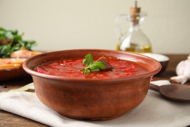 Photo of Stylish brown clay bowl with Ukrainian borsch served on wooden table
