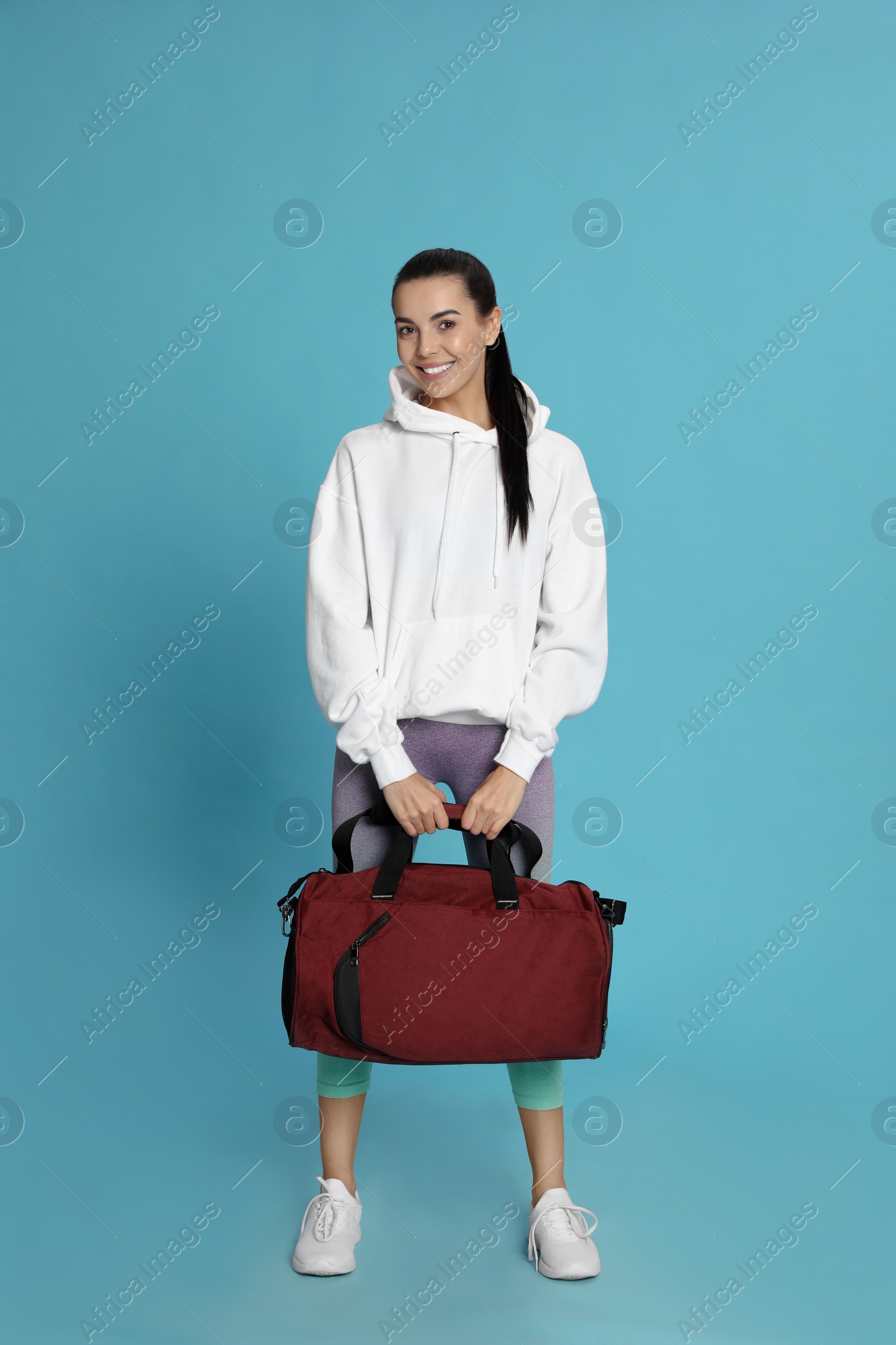 Photo of Beautiful woman with sports bag on light blue background