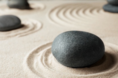 Photo of Zen garden stones on sand with pattern. Meditation and harmony