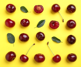 Photo of Sweet juicy cherries and leaves on yellow background, flat lay