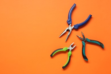 Photo of Different pliers on orange background, flat lay. Space for text