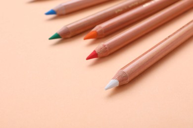 Photo of Colorful pastel pencils on beige background, closeup. Drawing supplies