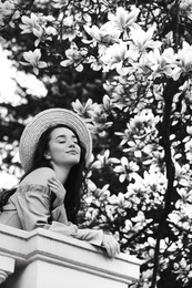 Beautiful woman near blooming tree outdoors. Black and white effect