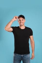 Happy man in black cap and tshirt on light blue background. Mockup for design