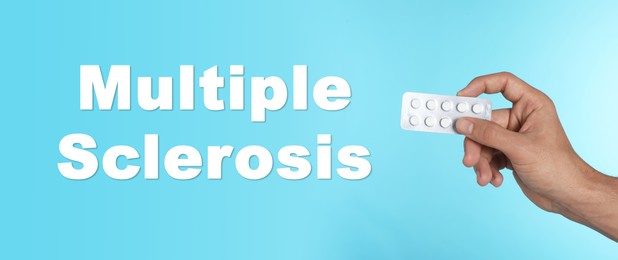 Image of Multiple sclerosis treatment. Man holding pills on light blue background, closeup