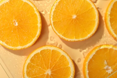 Photo of Slices of juicy orange and water on beige background, flat lay