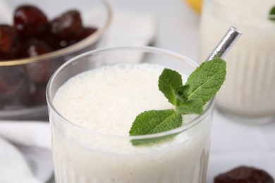 Glass of delicious date smoothie with mint on table, closeup