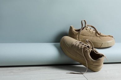Pair of stylish beige sneakers on floor against light grey background, space for text