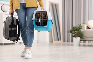 Photo of Travel with pet. Woman holding carrier with dog and backpack at home, closeup. Space for text