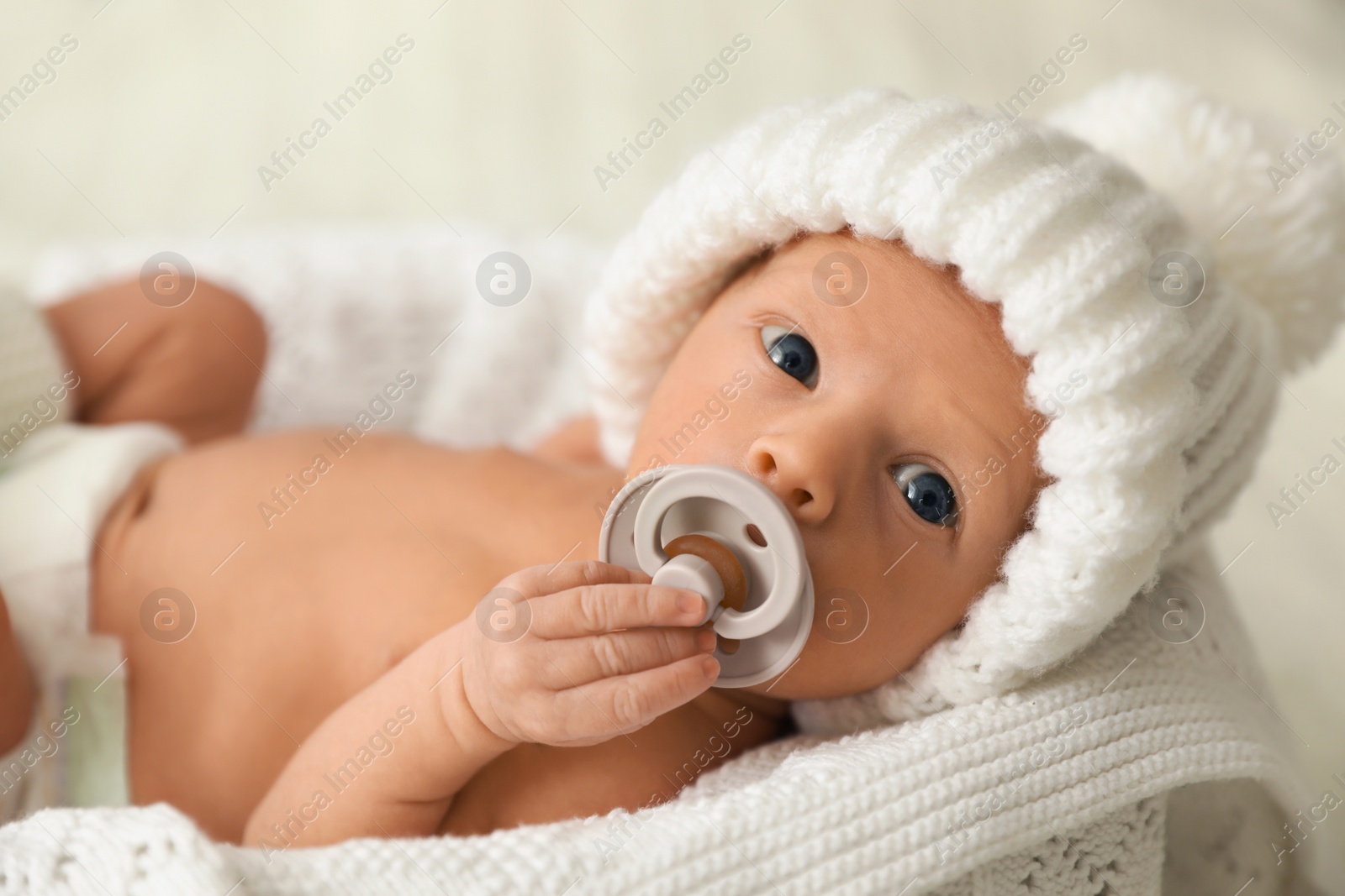 Photo of Adorable newborn baby with pacifier on white knitted plaid