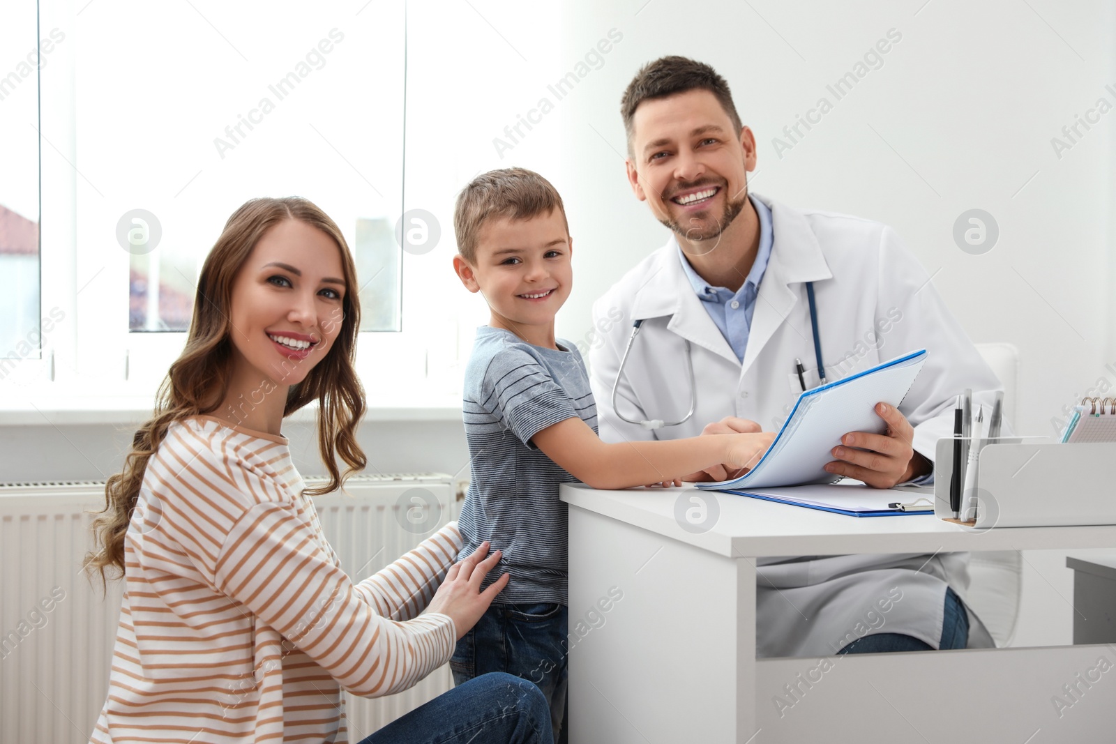 Photo of Mother and son visiting pediatrician. Doctor working with patient in hospital