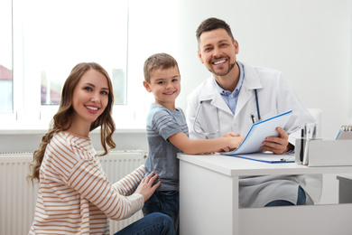 Photo of Mother and son visiting pediatrician. Doctor working with patient in hospital