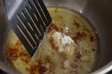 Photo of Cooking delicious turkey gravy. Ingredients and spatula in pot, closeup