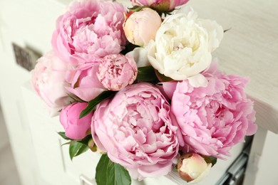 Photo of Bouquet of beautiful peonies in commode drawer indoors