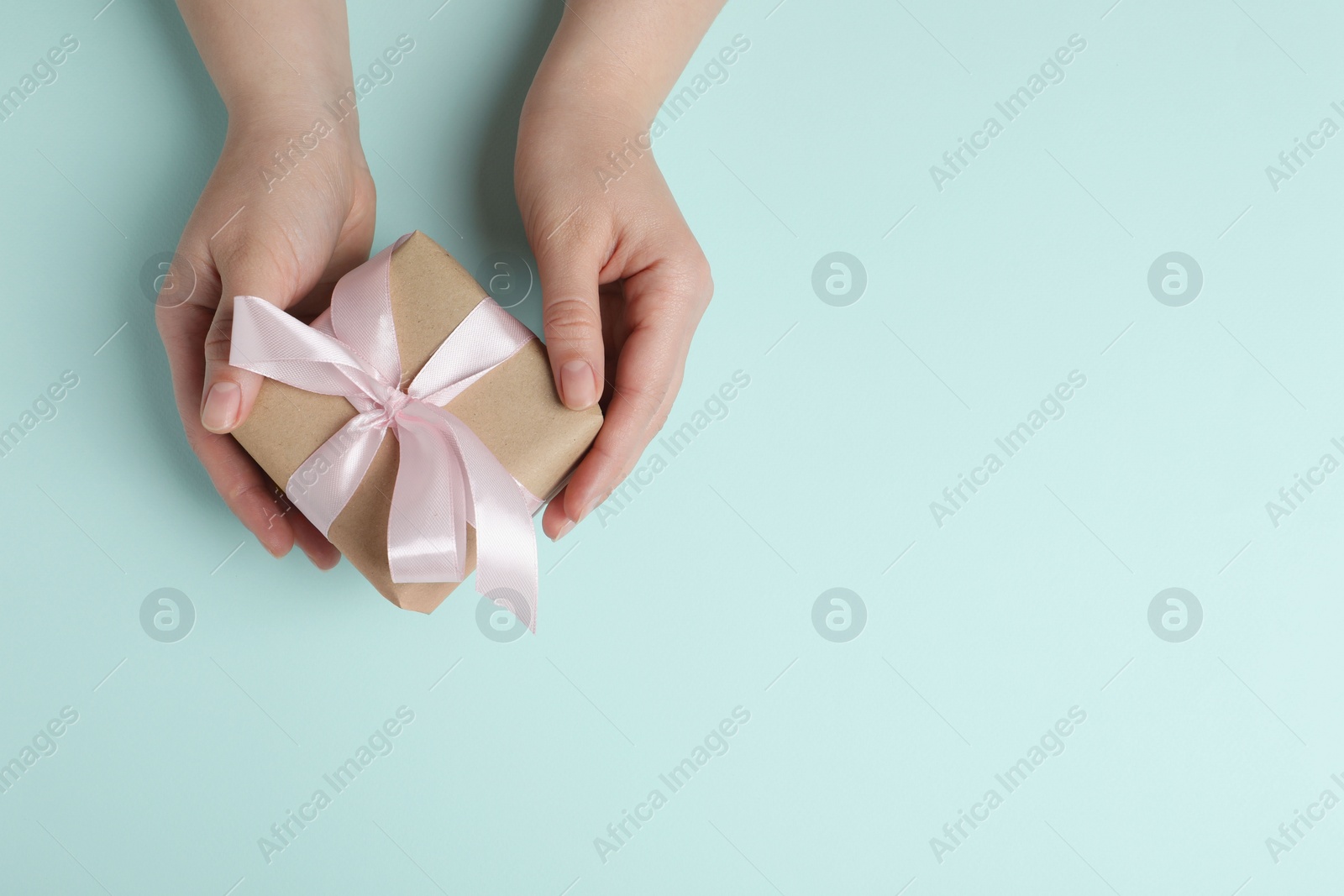 Photo of Woman with gift box on light blue background, top view. Space for text