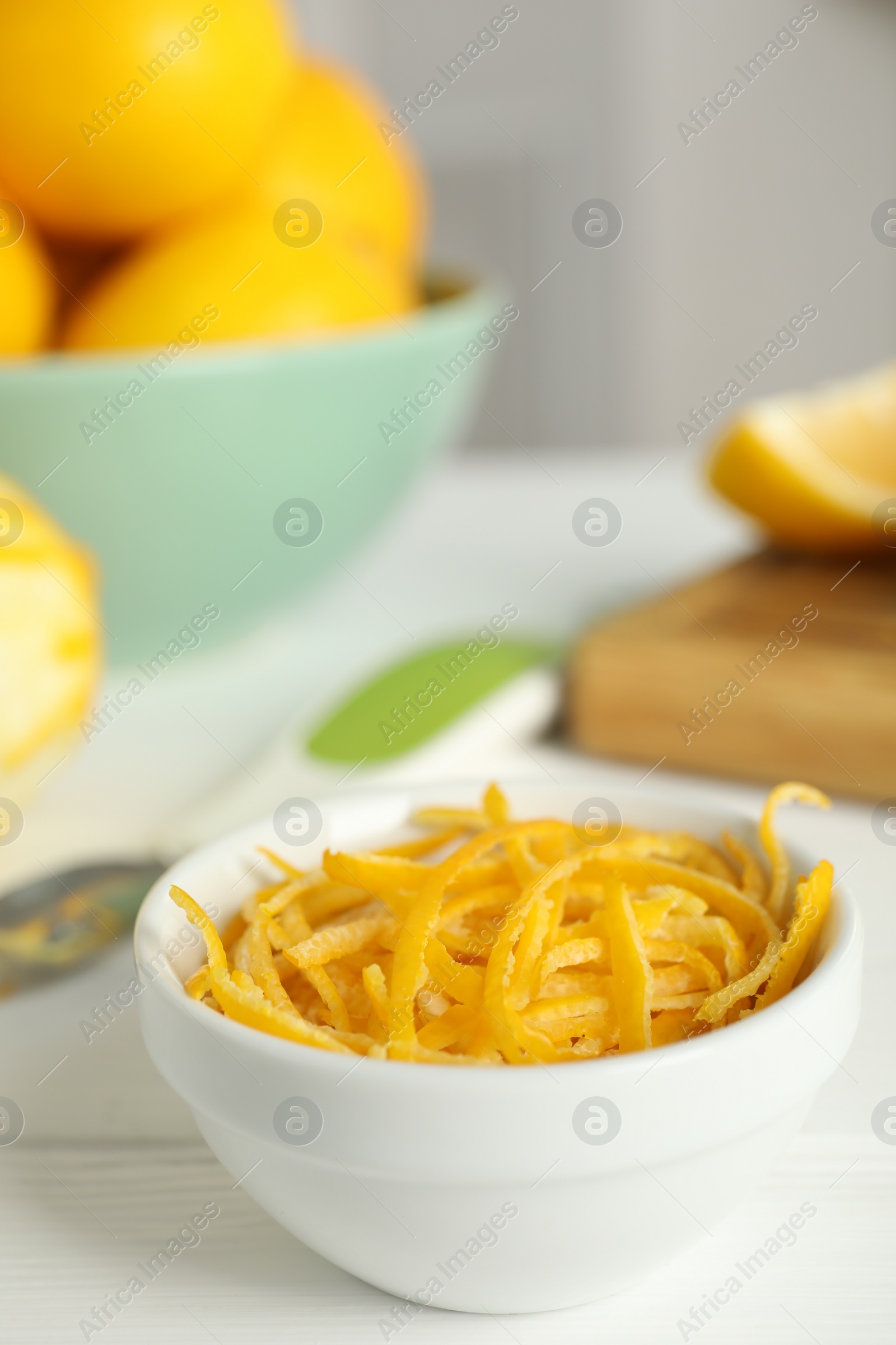 Photo of Grated lemon zest and fresh fruits on white wooden table, closeup