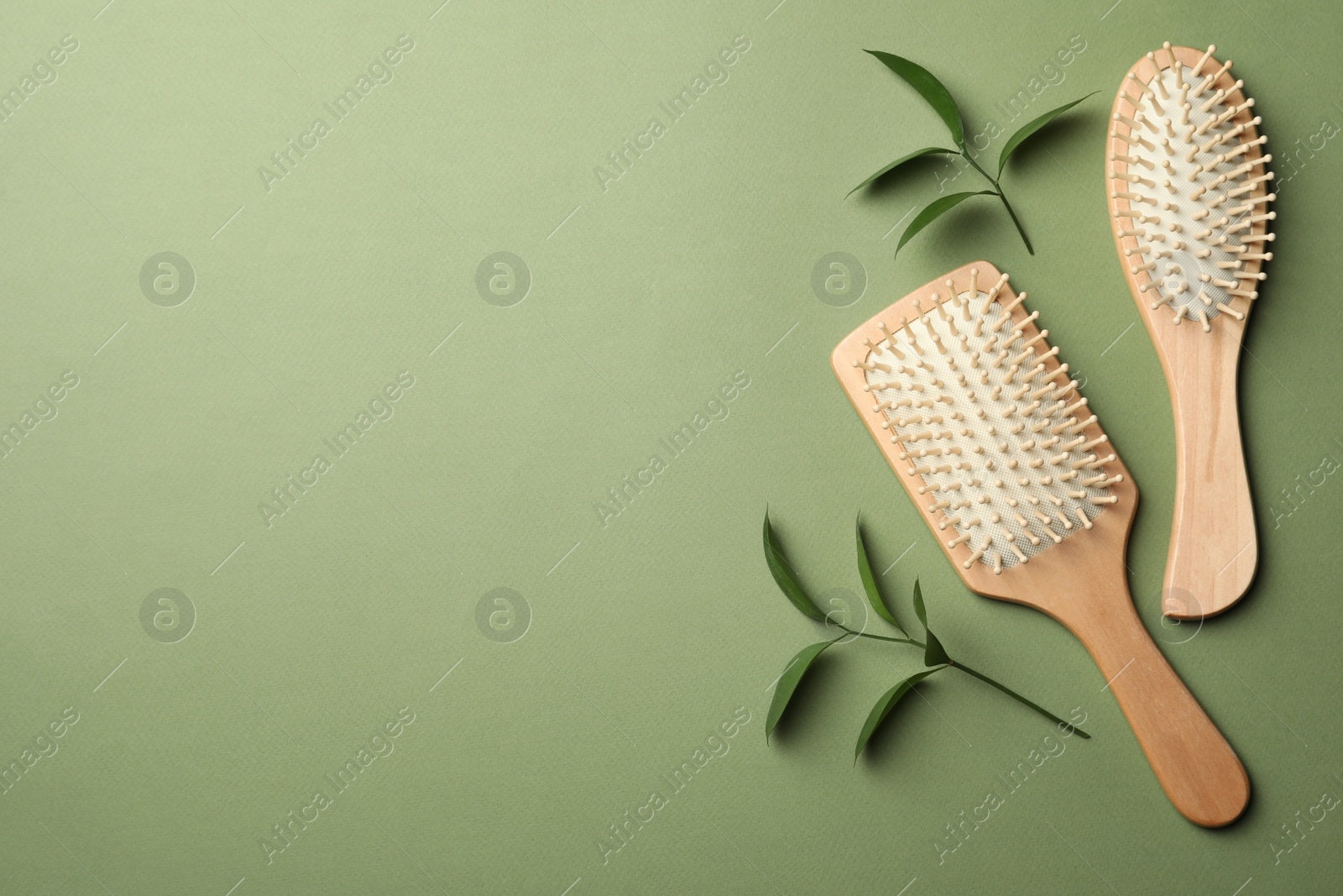 Photo of Bamboo hairbrushes and space for text on green background, flat lay. Conscious consumption
