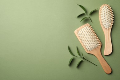 Bamboo hairbrushes and space for text on green background, flat lay. Conscious consumption