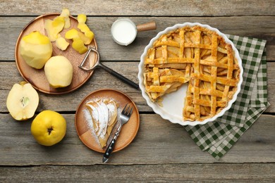 Photo of Tasty homemade quince pie, ingredients, peeler and fork on wooden table, flat lay