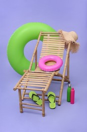 Photo of Deck chair, inflatable rings and other beach accessories on purple background. Summer vacation