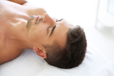 Photo of Young man undergoing acupuncture treatment in salon