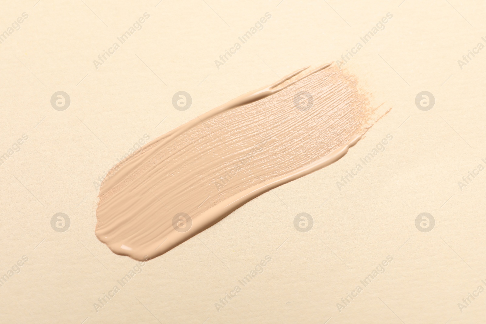 Photo of Smear of skin foundation on beige background, top view