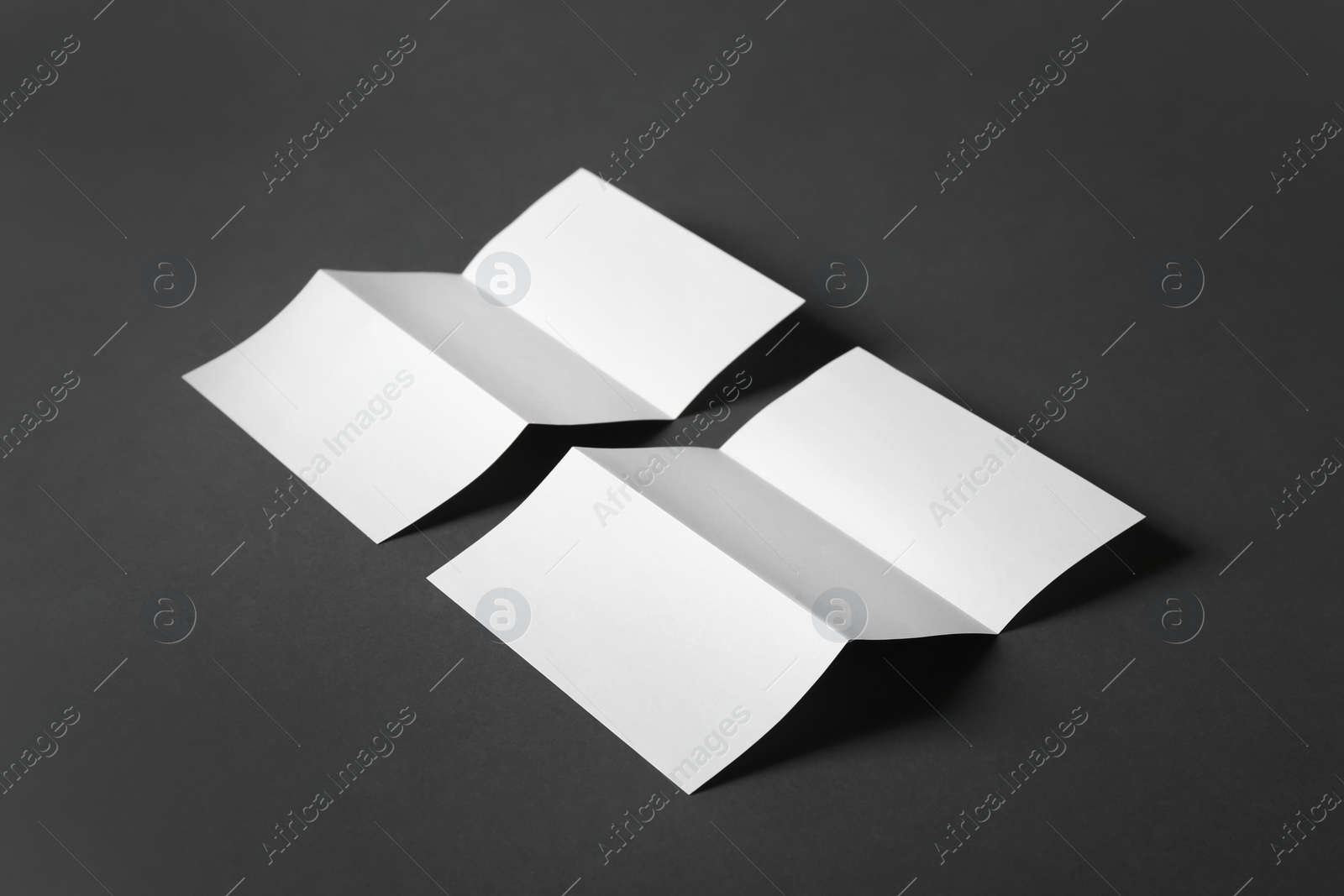 Photo of Two blank brochures on dark grey background. Mock up for design