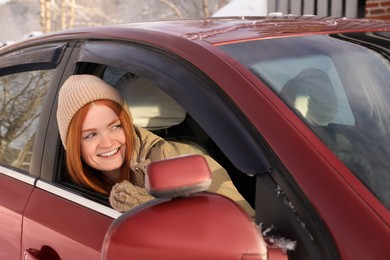 Happy young woman looking out of car window. Winter vacation