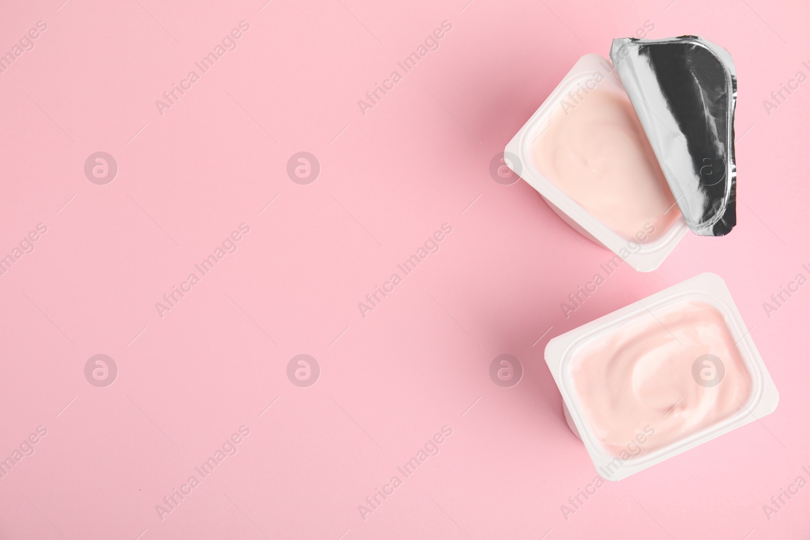 Photo of Tasty organic yogurt on pink background, flat lay. Space for text