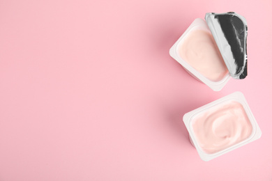 Photo of Tasty organic yogurt on pink background, flat lay. Space for text