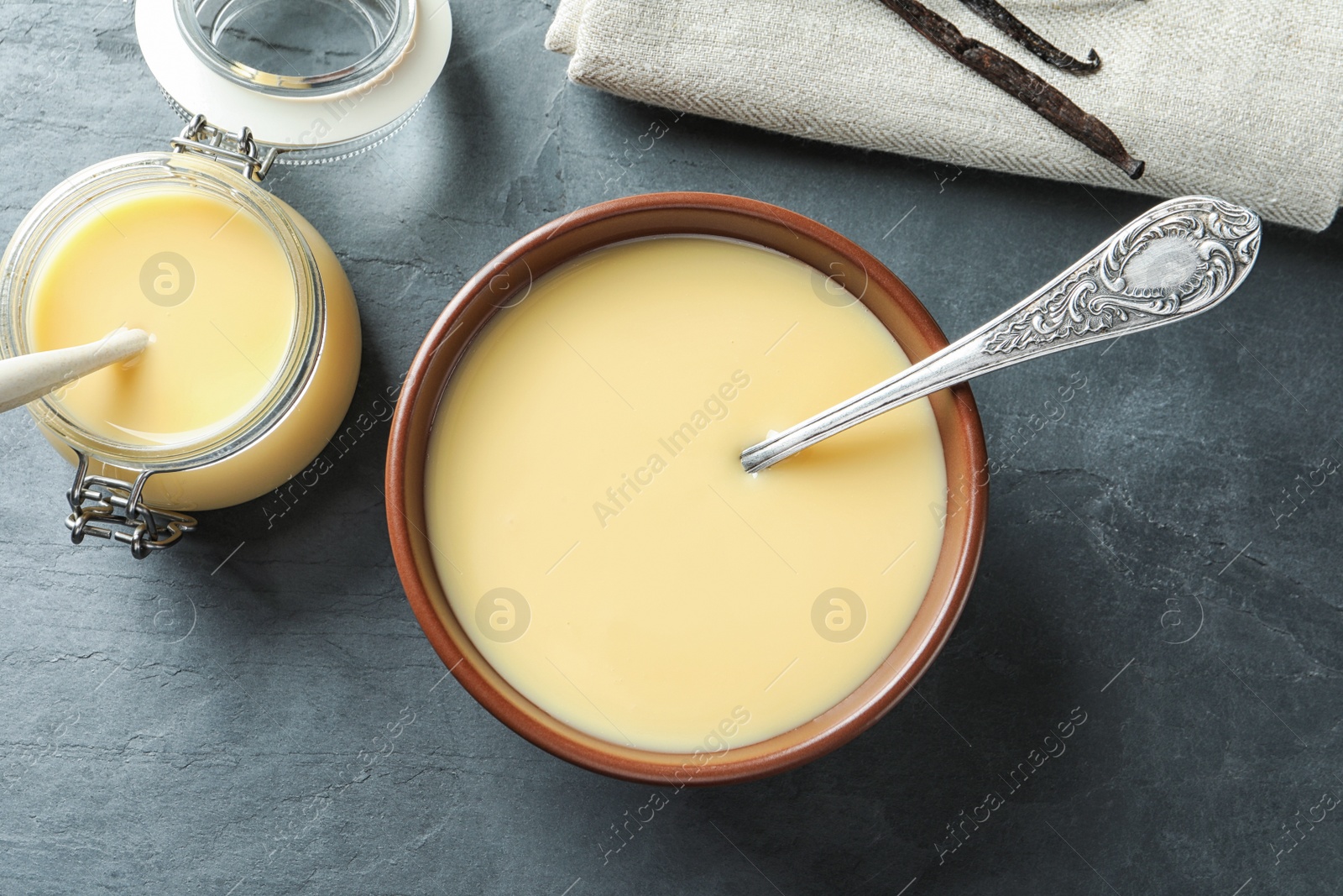 Photo of Flat lay composition with bowl and jar of condensed milk on grey background