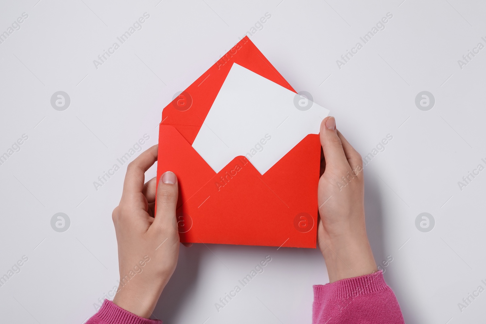 Photo of Woman holding letter envelope with card at white table, top view. Space for text