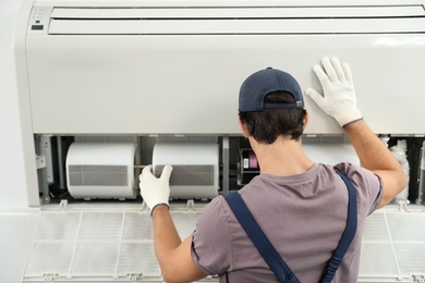 Photo of Technician installing and checking air conditioner indoors