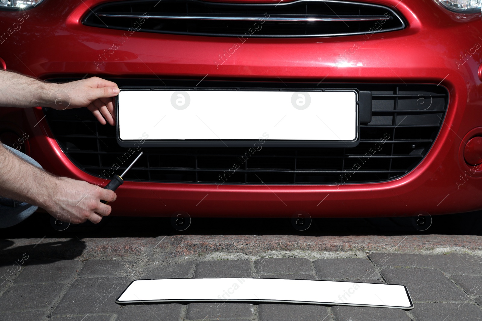 Photo of Man changing vehicle registration plate on car outdoors, closeup