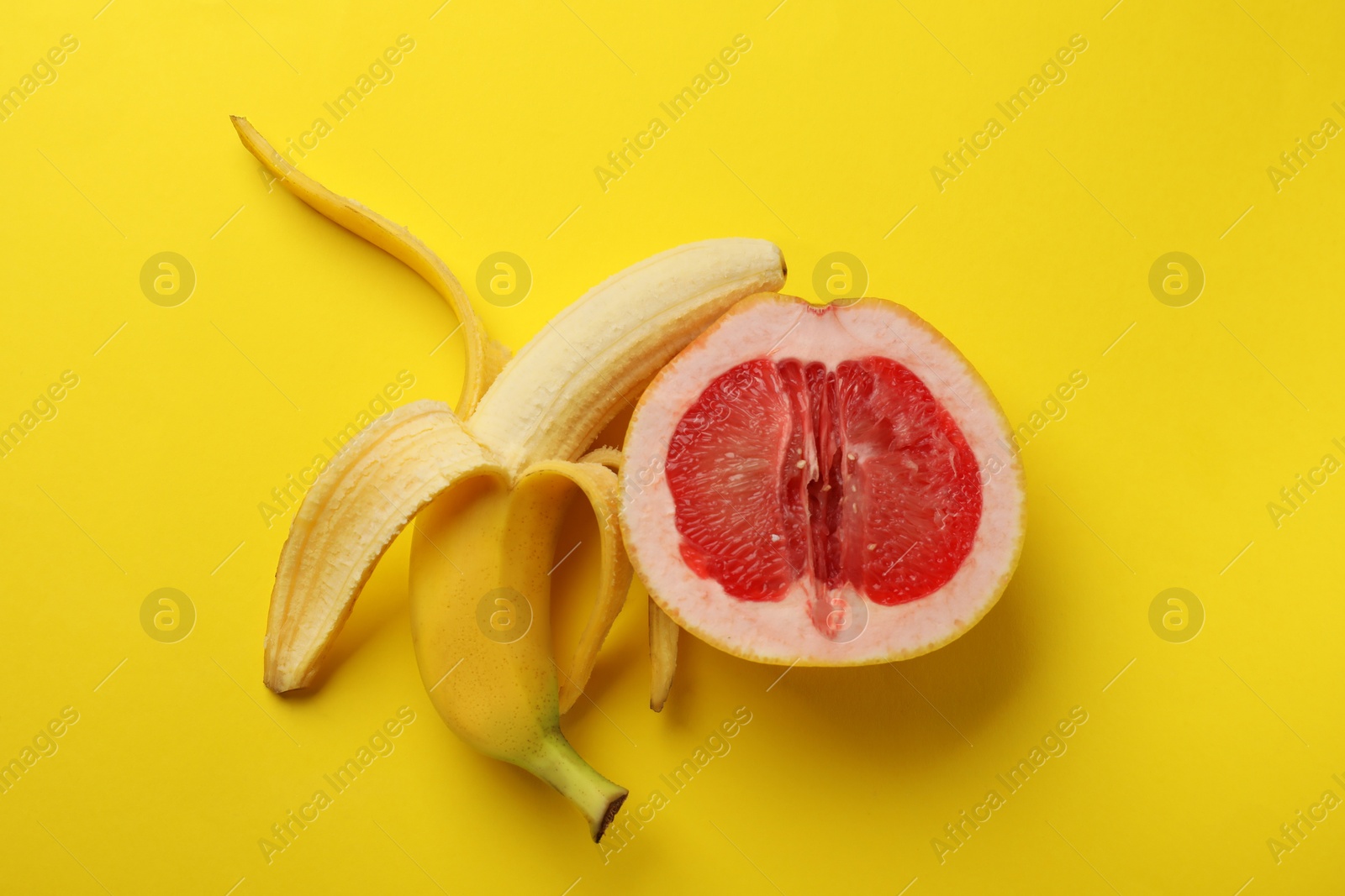 Photo of Banana and half of grapefruit on yellow background, flat lay. Sex concept