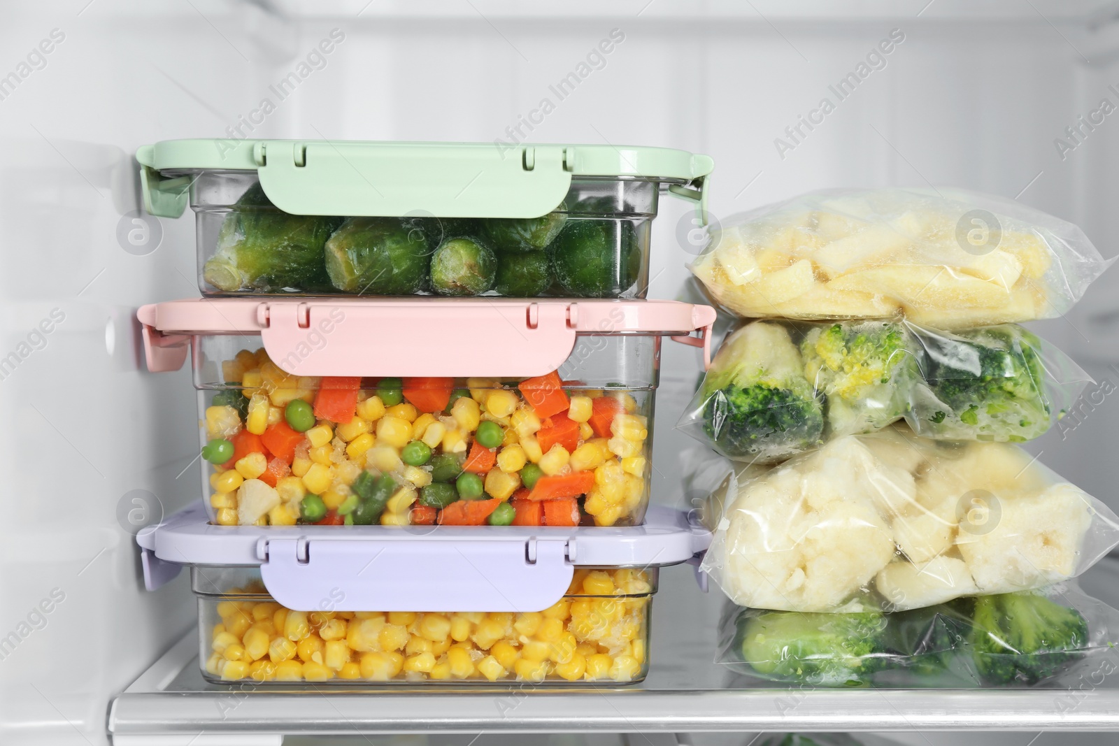 Photo of Plastic bags and containers with different frozen vegetables in refrigerator