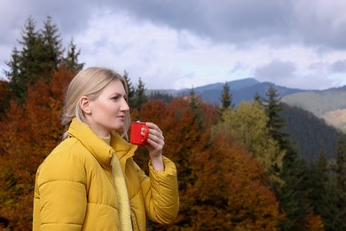 Photo of Young woman with mug of hot drink in mountains