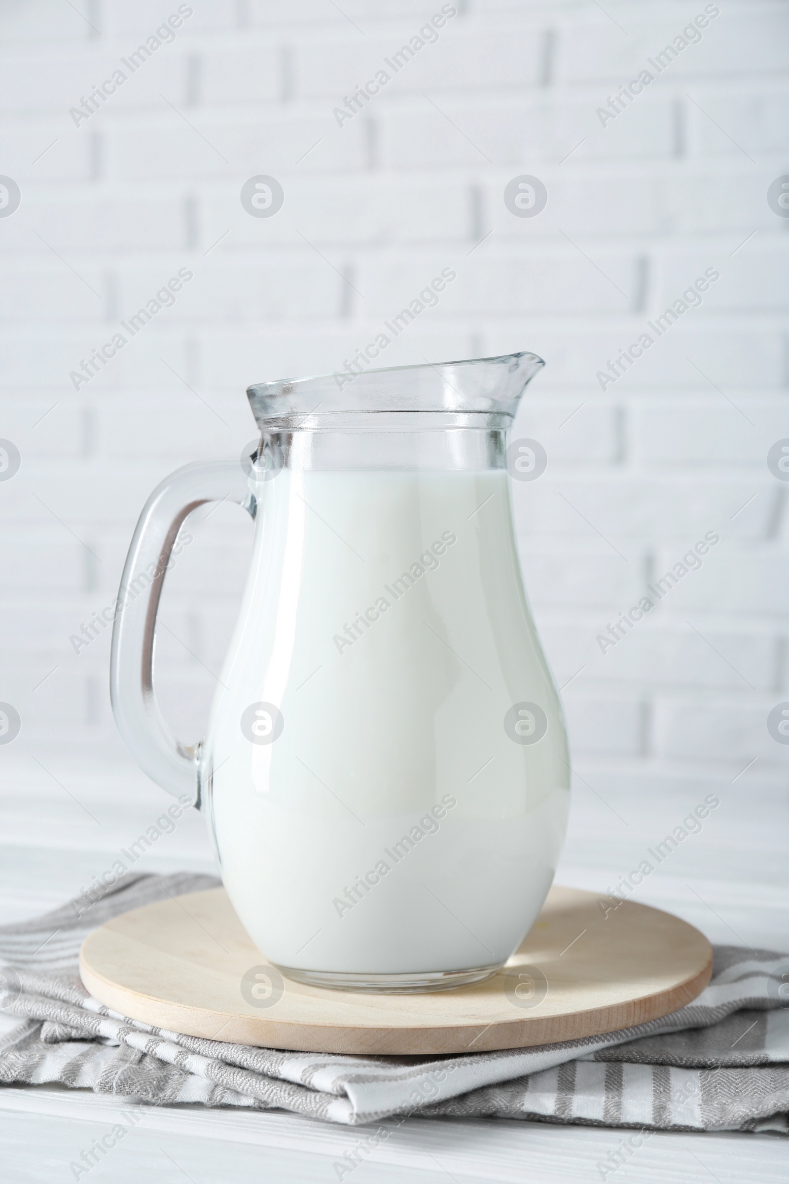 Photo of Jug of fresh milk on white wooden table