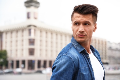 Photo of Portrait of handsome young man on city street. Space for text