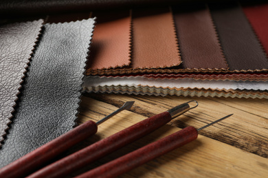 Photo of Leather samples and tools on wooden table, closeup