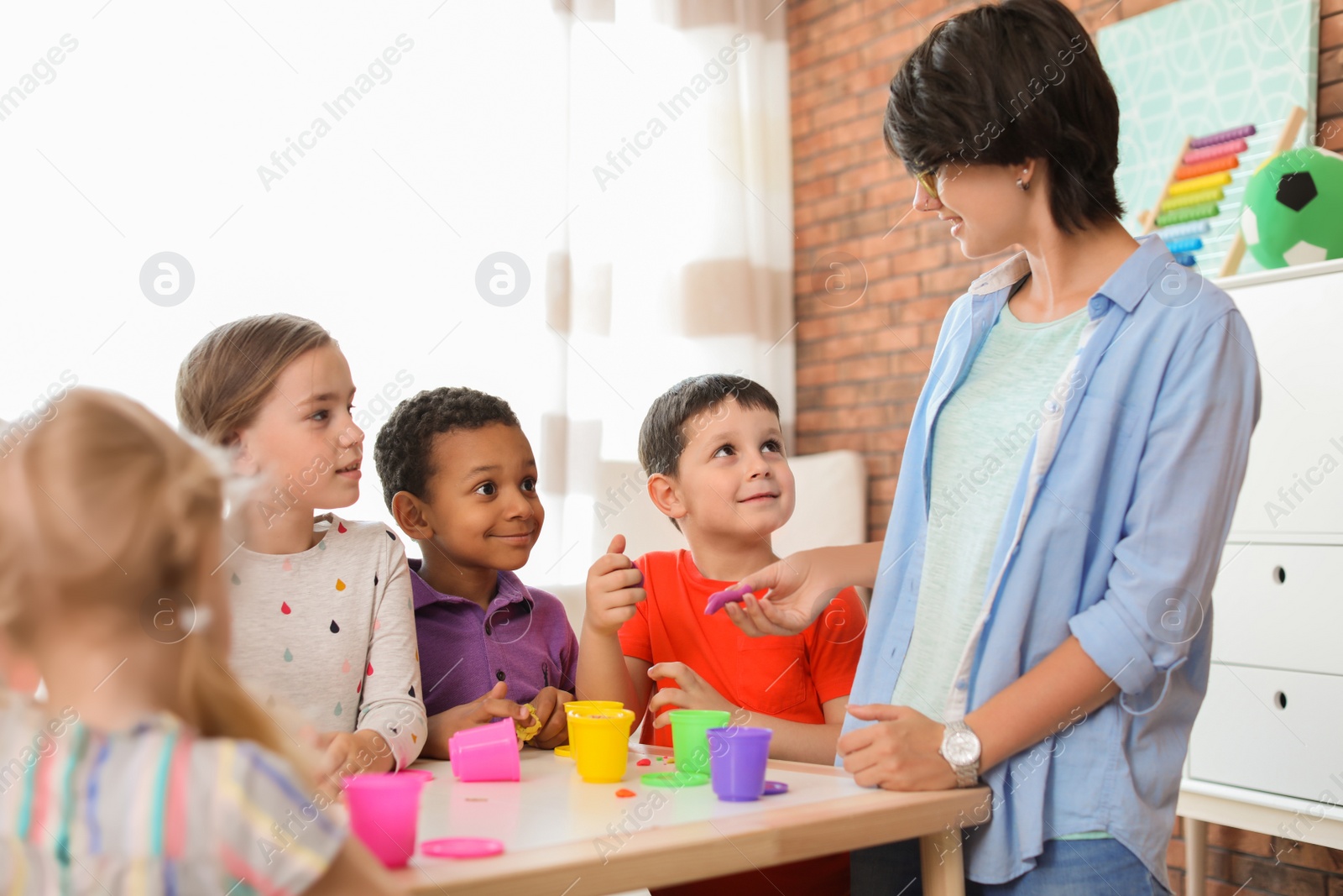 Photo of Young woman playing with little children indoors