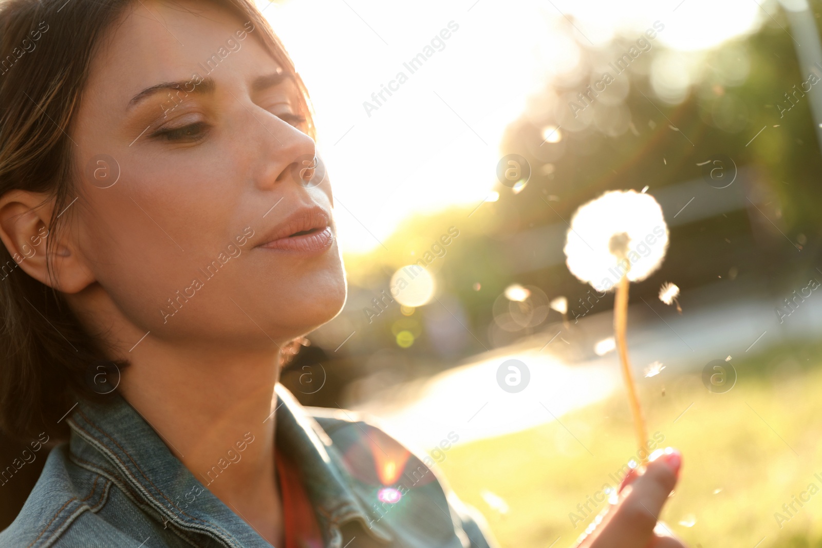 Photo of Young woman with dandelion in park on sunny day, closeup. Allergy free concept